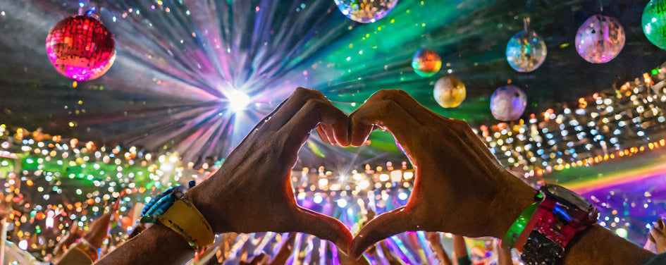 Image of someone making a heart sign with their hands at a festival 